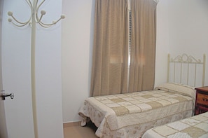 A bedroom with a single bed, a nightstand, a metal headboard, a white door, and a window with curtains. - Villa with private pool, town outskirts (CONIL DE LA FRONTERA)