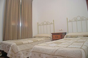 Ein Schlafzimmer mit zwei Einzelbetten, einem Nachttisch und einem Fenster mit Vorhängen.