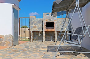 An outdoor patio area with a stone wall, a metal ladder, and a metal gate. - Villa with private pool, town outskirts (CONIL DE LA FRONTERA)
