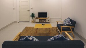 A living room with a sofa, a coffee table, a TV, and a chair. - Yindee Travellers Lodge (Nan)