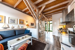 A modern interior with a wooden ceiling, a sofa, a dining table, and a kitchen area.