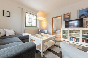 A modern living room with a sofa, a coffee table, a television, and a bookshelf.