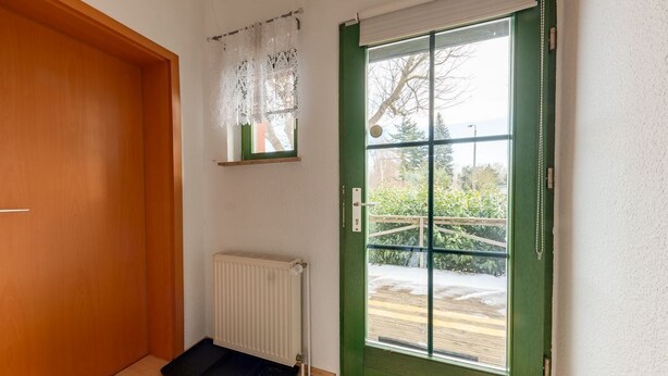 Una habitación con una puerta verde, un radiador blanco y un marco de madera.