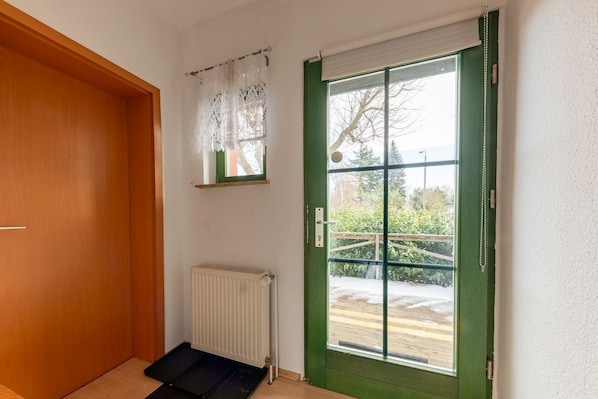 A room with a green door, a white radiator, and a wooden door frame.