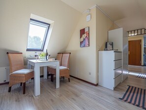 A dining area with a table and chairs, a window, a refrigerator, and a door leading to another room.