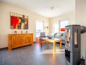 A modern living room with a sofa, coffee table, and a fireplace. - Thatched roof house Boddenblick - Boddenblick (Breege)
