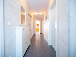 A hallway with a white dresser, a mirror, and a coat rack. - Thatched roof house Boddenblick - Boddenblick (Breege)