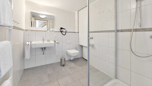 Une salle de bain moderne avec une douche à parois de verre, un lavabo blanc et des toilettes.