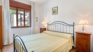 A bedroom with a bed, two bedside tables, a window, and a wall-mounted picture. - Lovely apartment in Rosolina Mare (RO) (Rosolina Mare (RO))