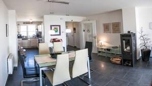 A modern kitchen with a dining area, featuring a central island, chairs, and a built-in stove. - Deichhaus Brisinga, Germany (Breege)
