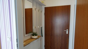 A hallway with a wooden door, a mirror, a plant, and a towel rack. - Vacation apartment Victoria with terrace and garden view - Holiday apartment Victoria with (Gustow)