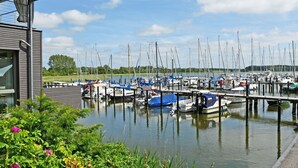 A marina with multiple boats docked at wooden piers, surrounded by greenery and a clear sky. - Vacation apartment Victoria with terrace and garden view - Holiday apartment Victoria with (Gustow)