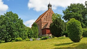 A church with a tall steeple, surrounded by trees and a grassy area. - Vacation apartment Victoria with terrace and garden view - Holiday apartment Victoria with (Gustow)