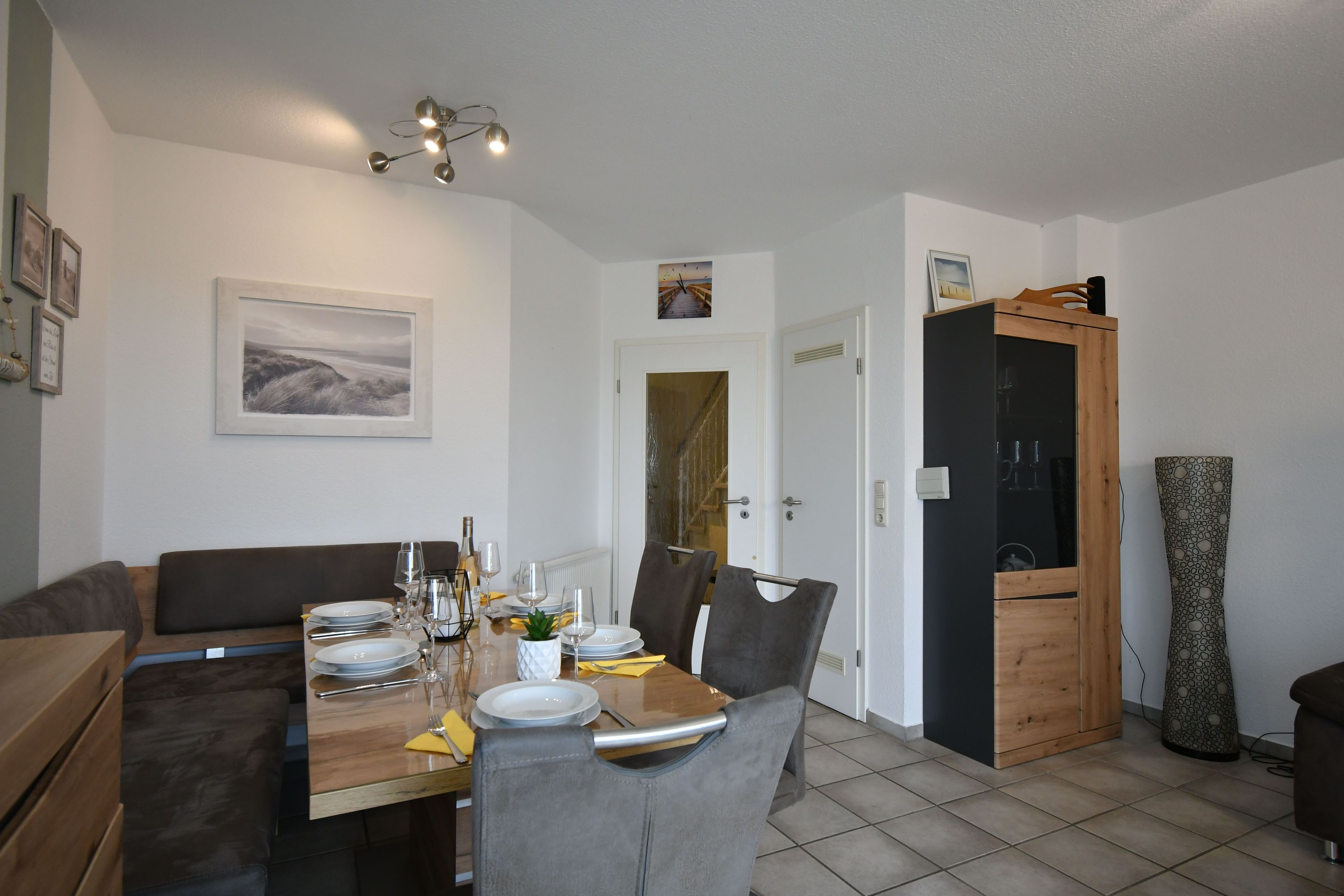 A dining area with a table set for four, a bench, and a cabinet with a mirror.