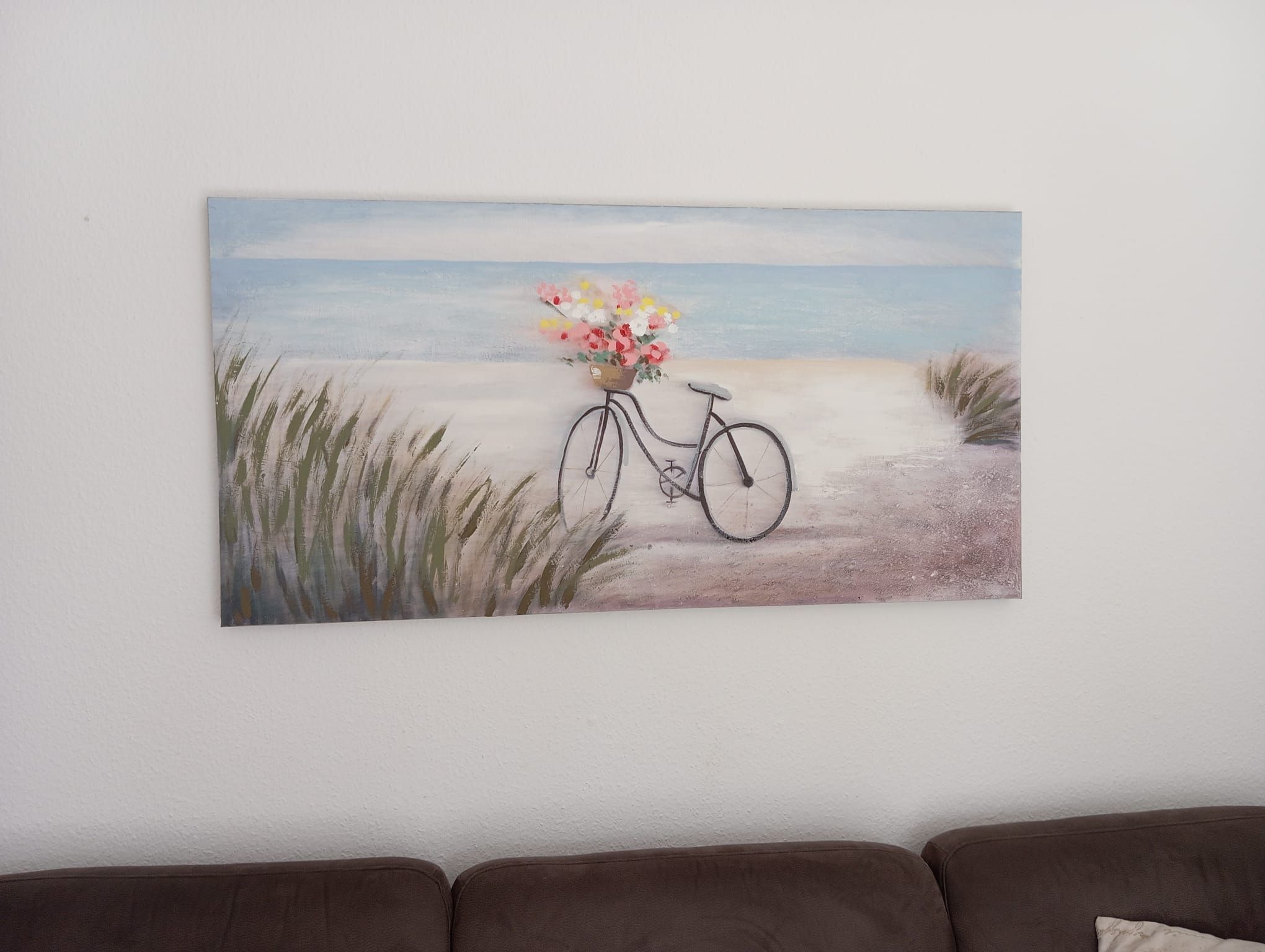 A painting of a bicycle with a basket of flowers on a path by the sea.
