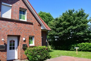 A red brick house with a white door, a mailbox, and a small garden.