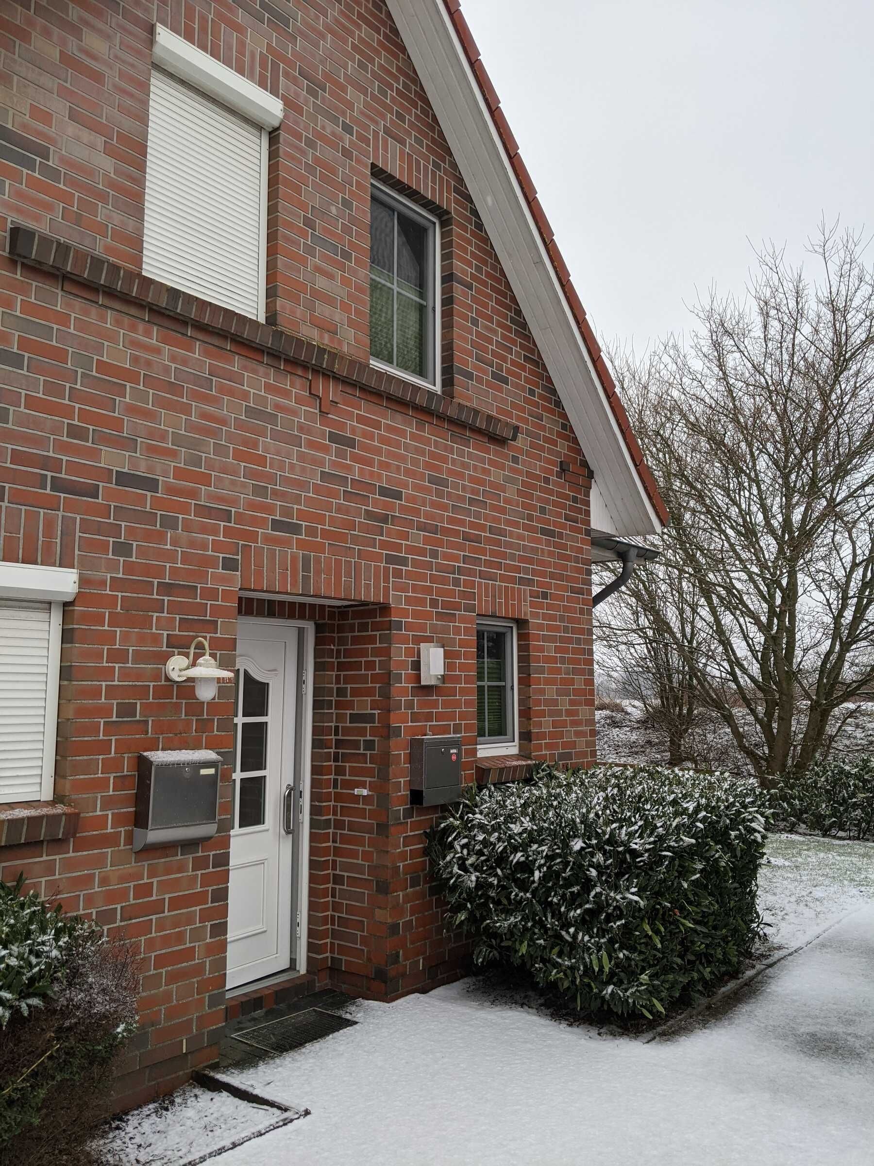 A two-story brick house with a white door, a window, and a mailbox.