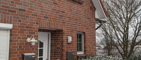 A two-story brick house with a white door, a window, and a mailbox.