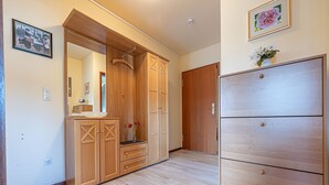 Een kamer met een houten garderobe, een spiegel en een kaptafel. Er staat een klein tafeltje met een bloevas.