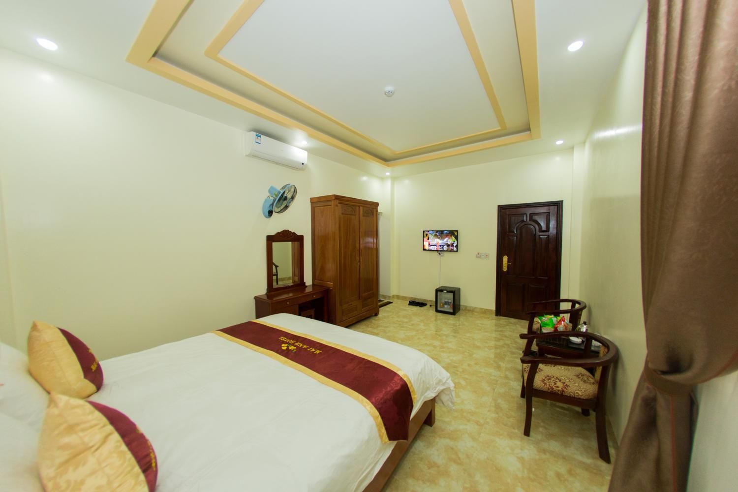 A hotel room with a bed, a wardrobe, a television, and a small table with a chair.