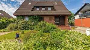 Une maison à deux étages, avec un toit en tuiles, des murs en briques et un porche à l’avant.
