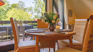 Un coin repas avec des meubles en osier, une table ronde et un vase de fleurs.
