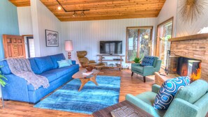 A cozy living room with a blue sofa, a green armchair, a wooden coffee table, and a fireplace.