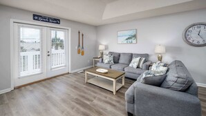 A living room with a grey sofa set, a wooden coffee table, and a wall clock.