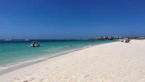 Une plage à l’eau turquoise et limpide, un rivage sablonneux et quelques bateaux.