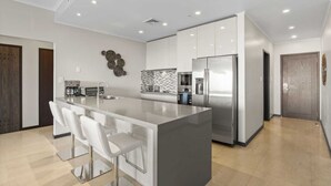 Une cuisine moderne dotée d’un îlot central, d’appareils électroménagers en acier inoxydable et d’un design minimaliste.