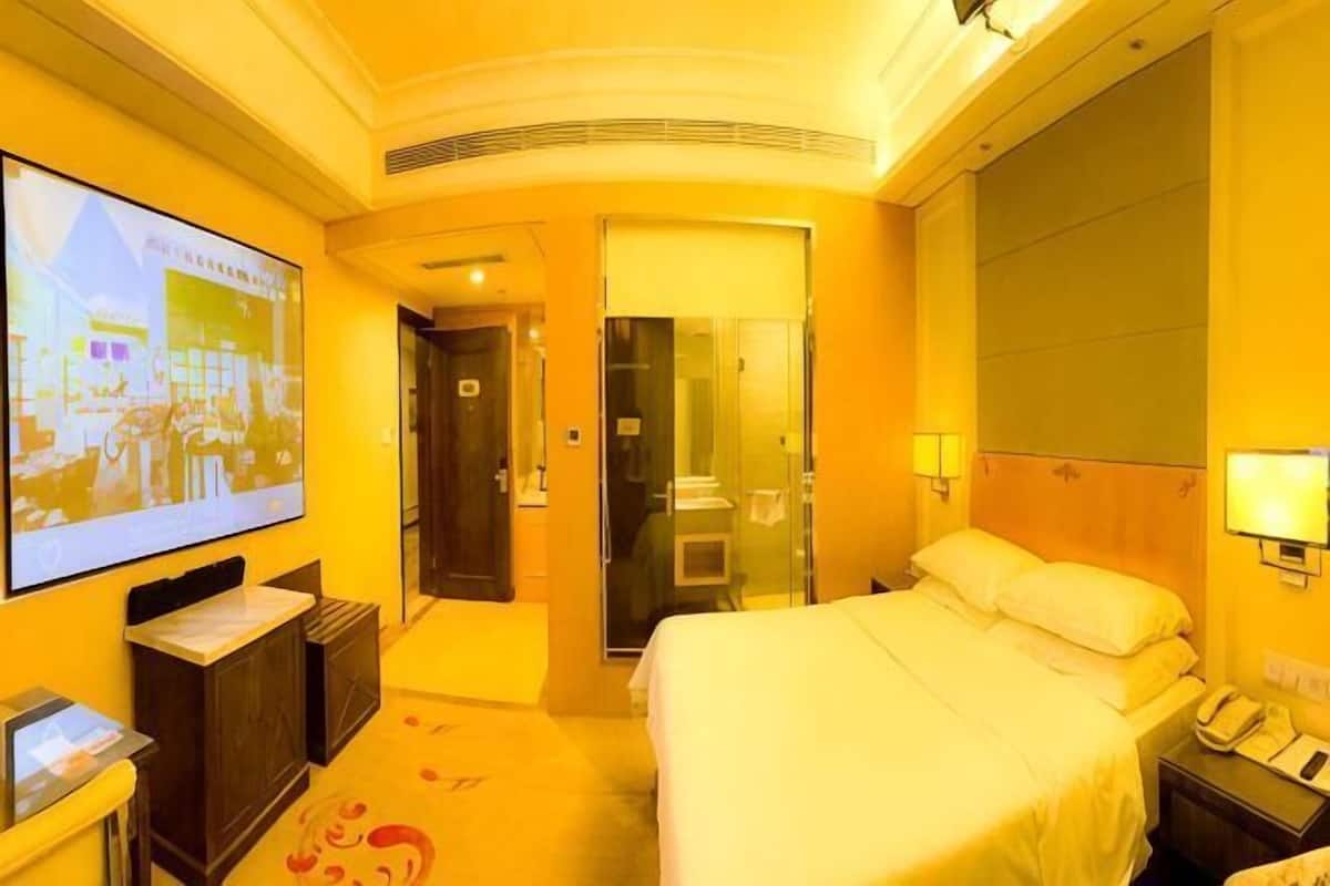 A hotel room with a bed, a TV, a desk, and a bathroom.