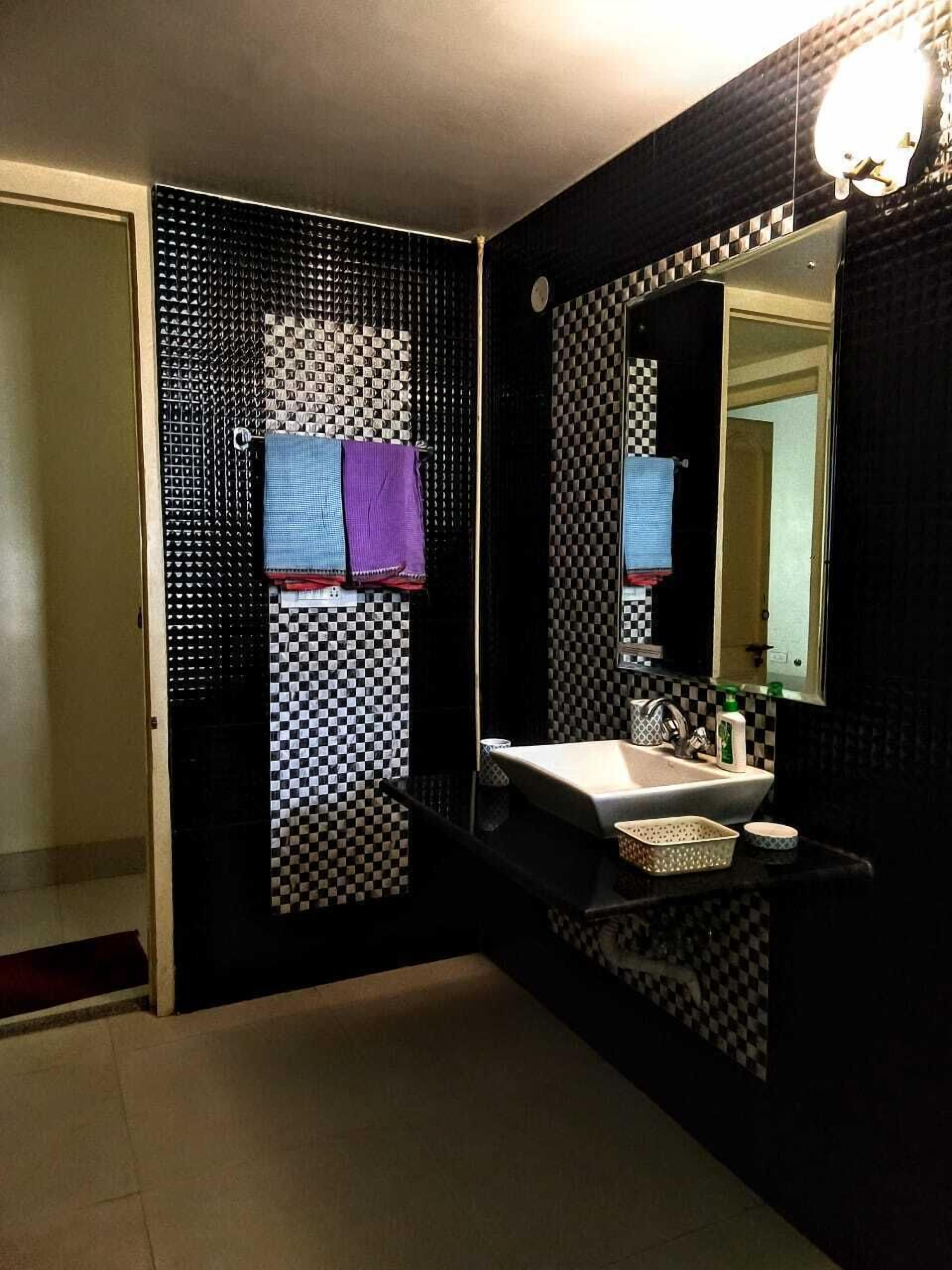 A bathroom with a checkered wall pattern, a sink, a mirror, and a towel rack.