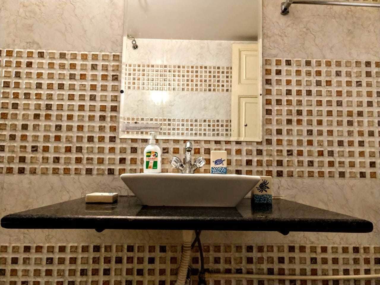Een badkamer met een wastafel, spiegel en betegelde muren.