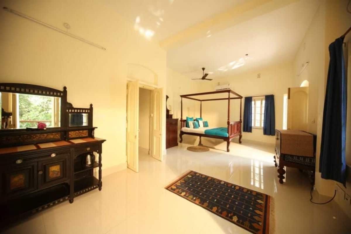 A spacious room with a large bed, a wooden dresser, and a ceiling fan.