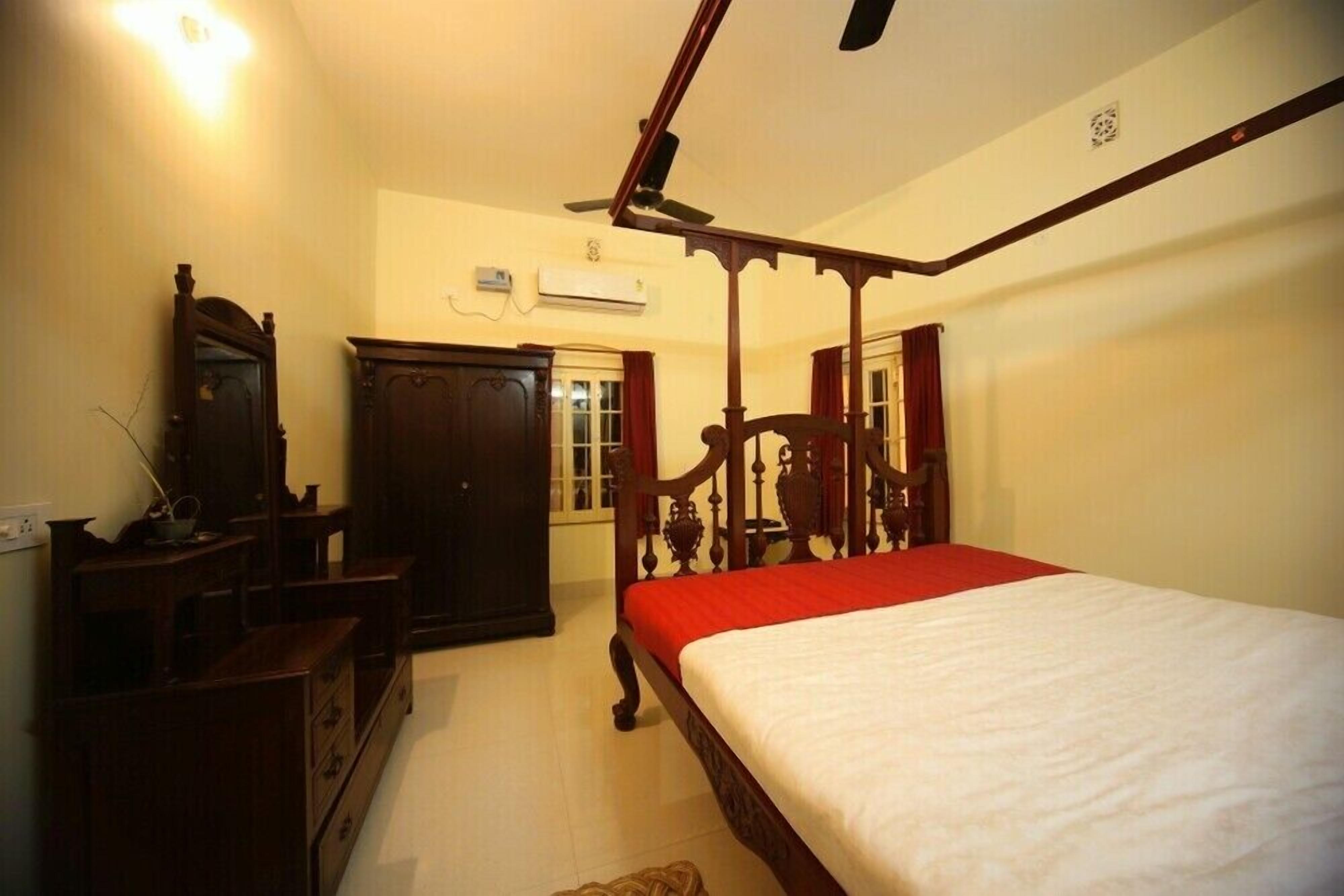 A bedroom with a four-poster bed, wooden furniture, and a ceiling fan.