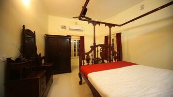 A bedroom with a four-poster bed, wooden furniture, and a ceiling fan.