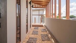 A corridor with a wooden ceiling, a pebble-tiled floor, and large windows on one side.