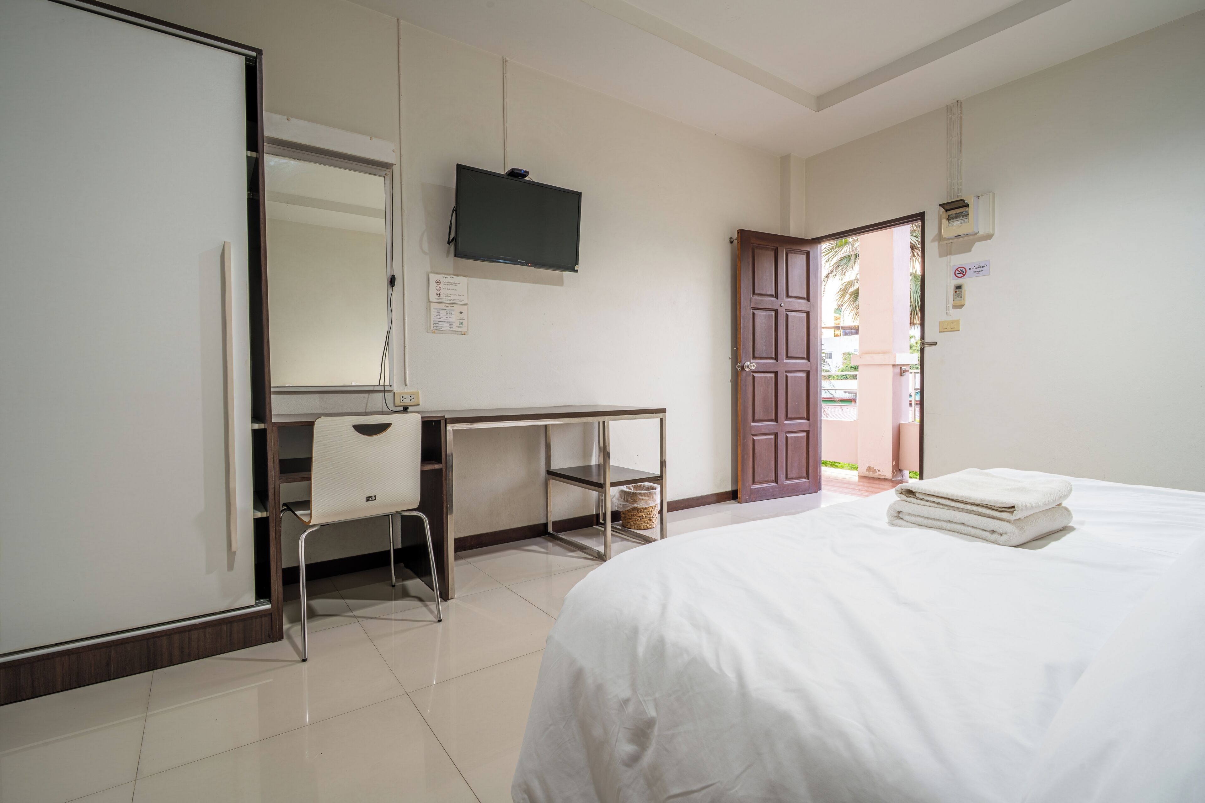 A hotel room with a bed, a desk, a chair, a television, and a wardrobe.