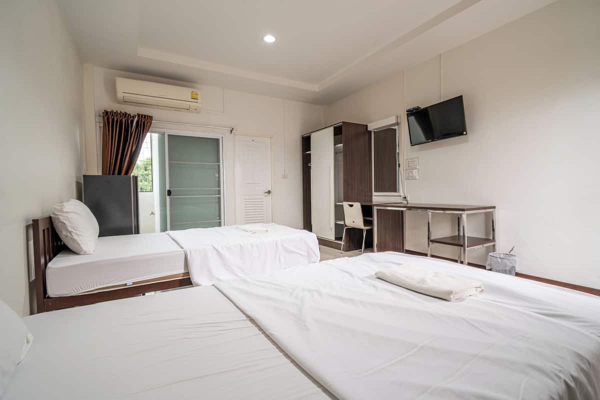 Ein Hotelzimmer mit zwei Betten, einem Schreibtisch, einem Fernseher und einem Kleiderschrank.