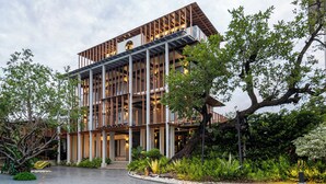 A modern multi-story building with a glass facade, surrounded by lush greenery and a well-maintained garden.