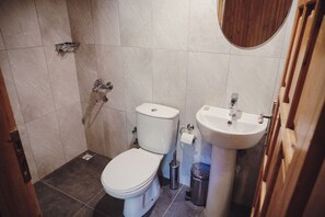 A small bathroom with a toilet, sink, and shower. - Base Bungalows (Kumluca)