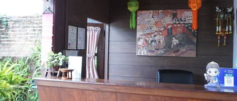 A reception desk with a wooden counter, a sign reading "INFORMATION", and a wall-mounted painting.