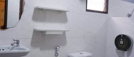 Un baño con inodoro, lavabo, espejo y un ventilador.