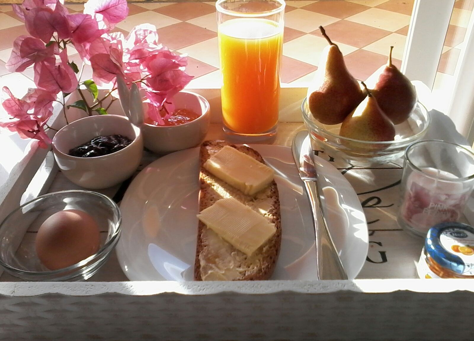 A breakfast tray with toast, butter, eggs, fruit, and juice.