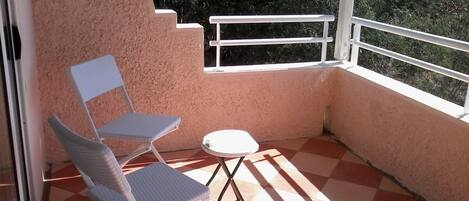 Ein Balkon mit Schachbrettboden, einem weißen Stuhl und einem kleinen Tisch.