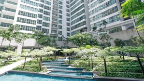 A modern high-rise building with multiple balconies and a landscaped area with a water feature. - Regalia Residence @ KLCC View Sky Pool by MC (Kuala Lumpur)