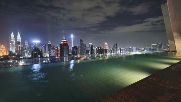 A nighttime cityscape with a prominent skyline, including two illuminated towers, over a calm body of water. - Regalia Residence @ KLCC View Sky Pool by MC (Kuala Lumpur)