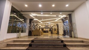 Eine moderne Hotellobby mit Empfangsschalter, Sitzgelegenheiten und einer Treppe zu den oberen Etagen.