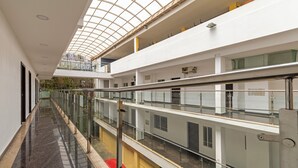 Ein mehrgeschossiges Interieur mit Glastrennwand, einer zentralen Wegeführung und einer hohen Decke mit Oberlicht.
