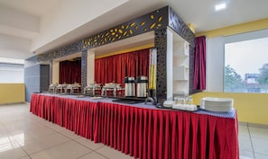 A buffet setup with a red tablecloth, multiple serving stations, and a decorative metal partition. - Treebo Grand Canyon By D2V (Kochi)